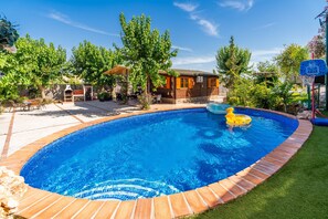 Patio trasero con piscina, zona de barbacoa y canasta de baloncesto.