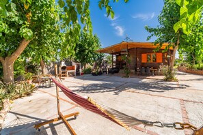 Une cabane en bois dotée d’une terrasse, entourée d’arbres et de plantes.
