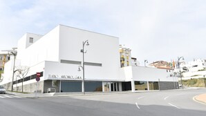 Un bâtiment moderne à la façade sobre, doté de grandes fenêtres et d’une enseigne indiquant « TEATRO ANTONIO GIA ».