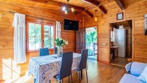 Une cabane en bois avec une table à manger, des chaises, un téléviseur et un lit.