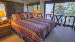 A bedroom with a large bed, two bedside lamps, a nightstand, and a balcony with a railing. - Vail Studio Condo Private Balcony, Loft, HSB312 (Vail)