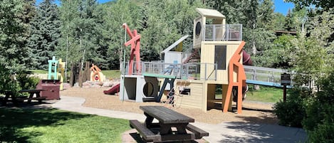 Een speelterrein met glijbanen, klimconstructies en picknicktafels.