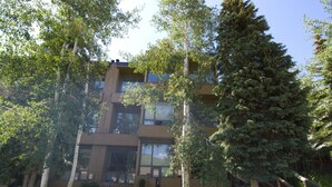 A multi-story building with a modern architectural design, surrounded by lush greenery and trees. - Vail Studio Condo Private Balcony, Loft, HSB312 (Vail)