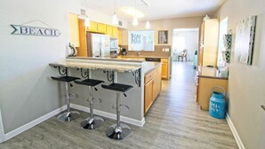 A kitchen with a bar area, wooden cabinets, and a blue water dispenser. - Dix-Sea-Land Delight: Close to beach, private pool, quiet street (Bradenton Beach)