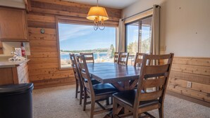 A wooden interior with a dining table and chairs, a trash bin, and a view of the outdoors. - Edgewater #10 , Magnificent Panoramic view of June Lake through lg picture window (June Lake)