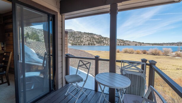 A wooden deck with a glass door leading to a room, a small table, and a chair. - Edgewater #10 , Magnificent Panoramic view of June Lake through lg picture window (June Lake)