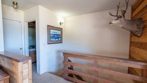 A hallway with a wooden bench, a mounted deer head, and a framed picture on the wall. - Edgewater #10 , Magnificent Panoramic view of June Lake through lg picture window (June Lake)