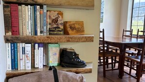A cozy room with a wooden bookshelf, a cushioned bench, and a dining area with wooden chairs and a table. - Lakefront retreat with big views | Freshly renovated (June Lake)