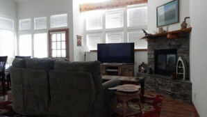 A living room with a fireplace, a television, and a sofa. - Hideaway #103, views of Carson Peak (June Lake)