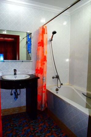 A bathroom with a sink, mirror, shower, and patterned floor tiles. - Vanne Hotel (Battambang)