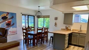 A modern kitchen with a central island, wooden dining table, and chairs. - Edgewater #4 NEWLY RENOVATED! “GARAGE PARKING“ EN-SUITE KING SIZE BED (June Lake)