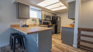 A modern kitchen with grey cabinets, a wooden countertop, and a built-in microwave. - Edgewater #4 NEWLY RENOVATED! “GARAGE PARKING“ EN-SUITE KING SIZE BED (June Lake)