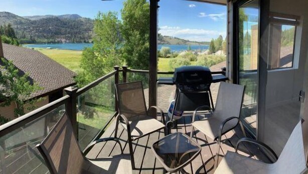 A balcony with a view of a lake and mountains, furnished with chairs and a table. - Edgewater #4 NEWLY RENOVATED! “GARAGE PARKING“ EN-SUITE KING SIZE BED (June Lake)