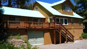 A two-story log cabin with a covered porch and a staircase leading to the upper level. - Smith Mountain Home CUP18-009 AP 18-004 (June Lake)