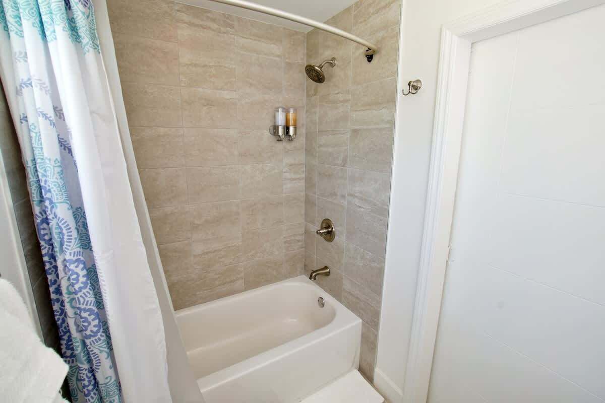 A bathroom with a bathtub, shower, and a towel rack.