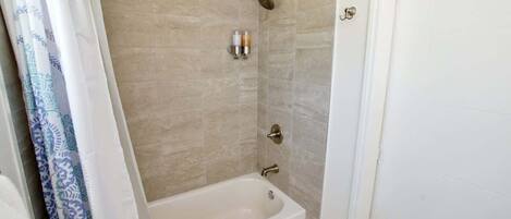 A bathroom with a bathtub, shower, and a towel rack.