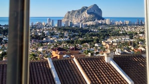 A view from a window overlooking a cityscape with a prominent mountain and buildings.