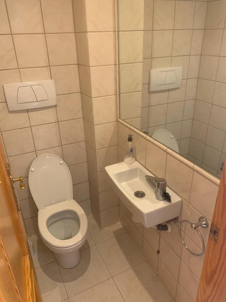 Un baño pequeño con inodoro, lavamanos y espejo.