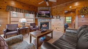 A cozy cabin interior with a fireplace, leather furniture, and a television. - Free Tickets | Million Dollar View, Easy Access, Arcade, Fireplace, Hot Tub (Gatlinburg)