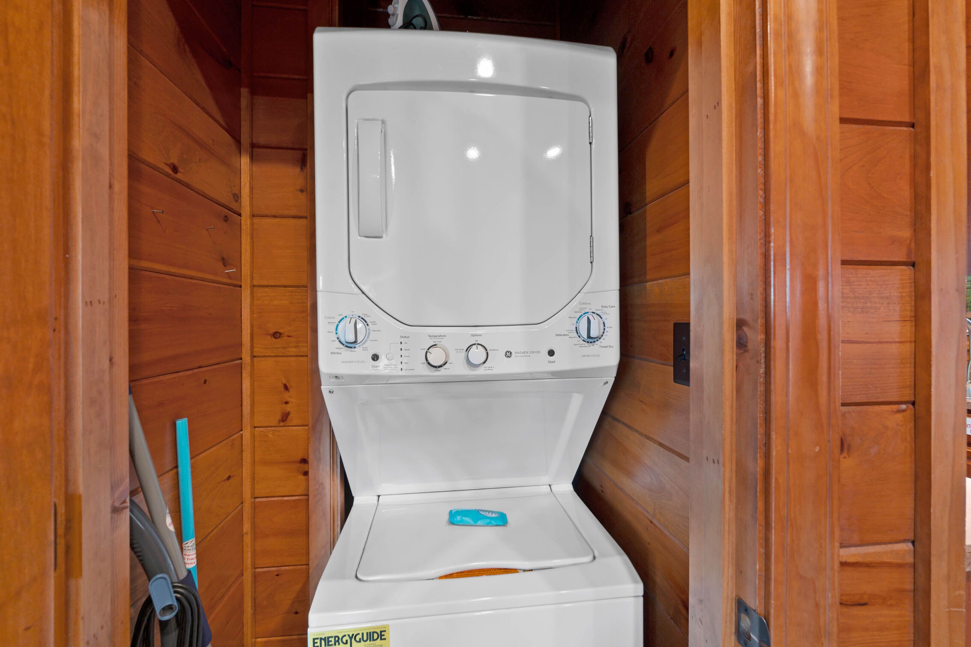 Una lavadora blanca con paneles de control y dispensador de detergente en una cabaña de madera.