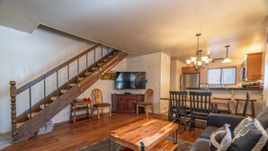 Un vaste salon agrémenté d’un escalier en bois, d’un coin repas et d’une cuisine équipée d’appareils électroménagers modernes.