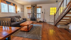 Un salon chaleureux avec une cheminée, des meubles en bois et un escalier.