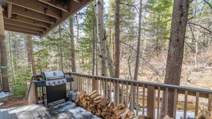 Une terrasse couverte avec un barbecue et une pile de bois de chauffage.