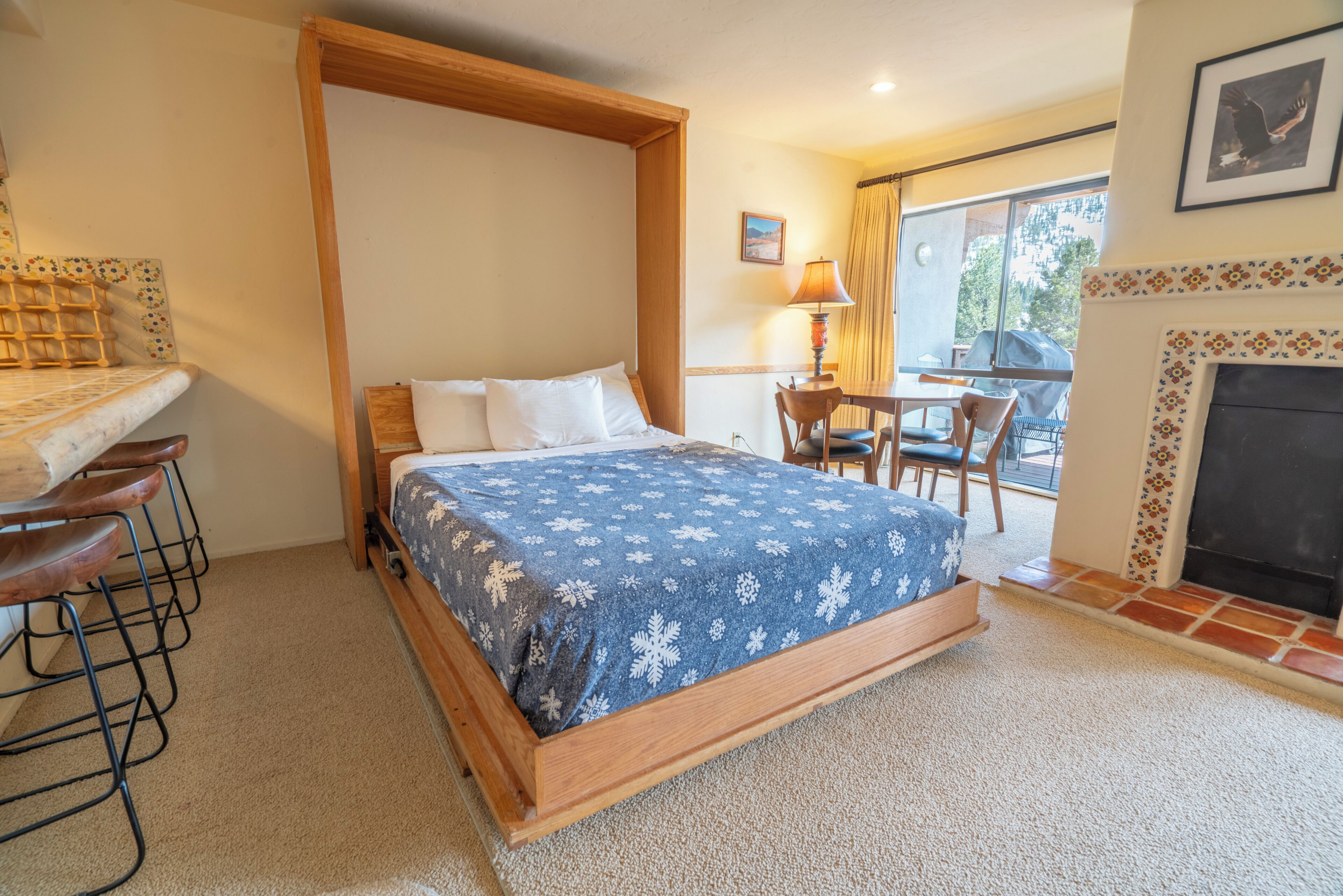 Un dormitorio con cama, escritorio, sillón y chimenea, con vistas al exterior.