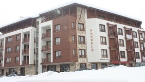 Un hotel de varios pisos con un llamativo letrero 'PREDELA', balcones y suelo cubierto de nieve.