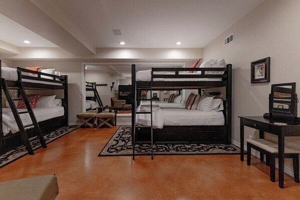 A room with bunk beds, a desk, and a chair.