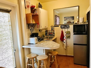 A kitchen with a white countertop, wooden stools, a refrigerator, and a microwave. - CUTE STUDIO/EAST HOLLYWOOD/2 MILES TO THE BEACH/FREE PARKING/BBQ/M-11 (Hollywood)
