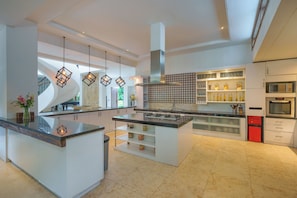 Une cuisine moderne dotée d’un îlot central, d’appareils électroménagers intégrés et de luminaires suspendus.