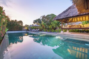 A clear swimming pool with lounge chairs and a thatched-roof structure. - The ultimate Bali beachside getaway at Villa Kaira Estate, a 7-bedroom luxury villa in Berawa, Canggu. The Estate offers daily breakfast, a full-time private chef, airport transfers, complimentary massages, housekeeping, and a dedicated driver. (North Kuta)