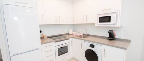 A modern kitchen with white cabinetry, a built-in oven, microwave, and dishwasher.