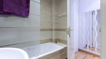 Een bad/douchecombinatie, een bidet, handdoeken, zeep