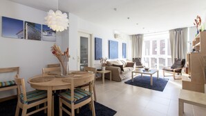 A modern living room with a dining area, featuring a round wooden table, chairs, a sofa, and a coffee table. - Apartment in the center of Madrid, Rastro (Madrid)