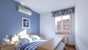 A bedroom with a bed, bedside table, lamp, and a window with a view of buildings. - Apartment in the center of Madrid, Rastro (Madrid)