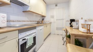 A modern kitchen with white cabinets, a built-in oven, a dishwasher, and a wooden countertop. - Apartment in the center of Madrid, Rastro (Madrid)