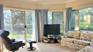 A living room with a sofa, a chair, a television, and a bookshelf.