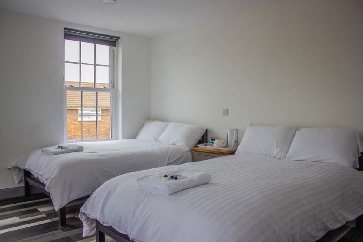 A hotel room with two beds, a large window, and a wooden floor.