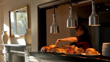A person serving food at a counter with hanging lights above.