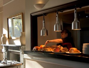 Une personne servant de la nourriture derrière un comptoir, avec des lampes suspendues au-dessus.