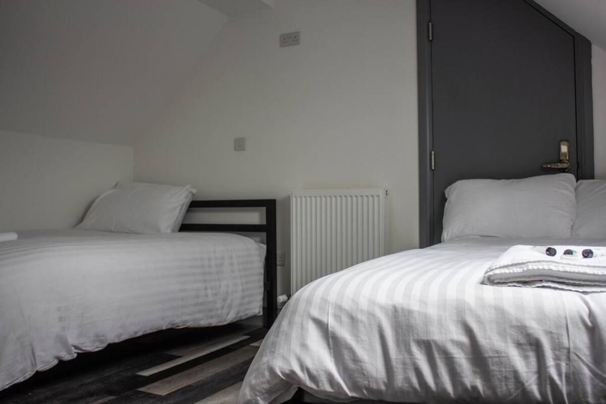 A bedroom with two single beds, a radiator, and a door.