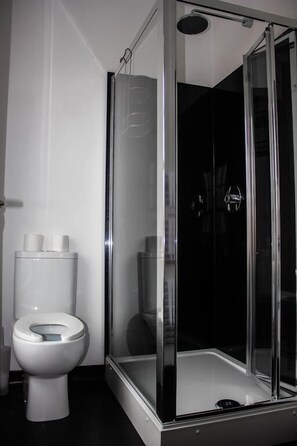 Une salle de bain avec une douche à parois de verre, des toilettes et un lavabo blanc.