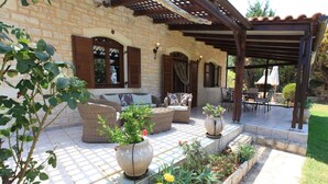 A covered patio area with outdoor furniture, a stone wall, and a pergola. - Villa Persephone, drofnah and beach (Rethymnon)
