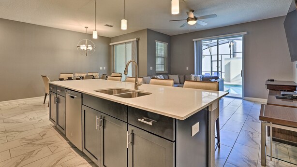 Een moderne keuken met een groot kookeiland, inbouwapparatuur en hanglampen.