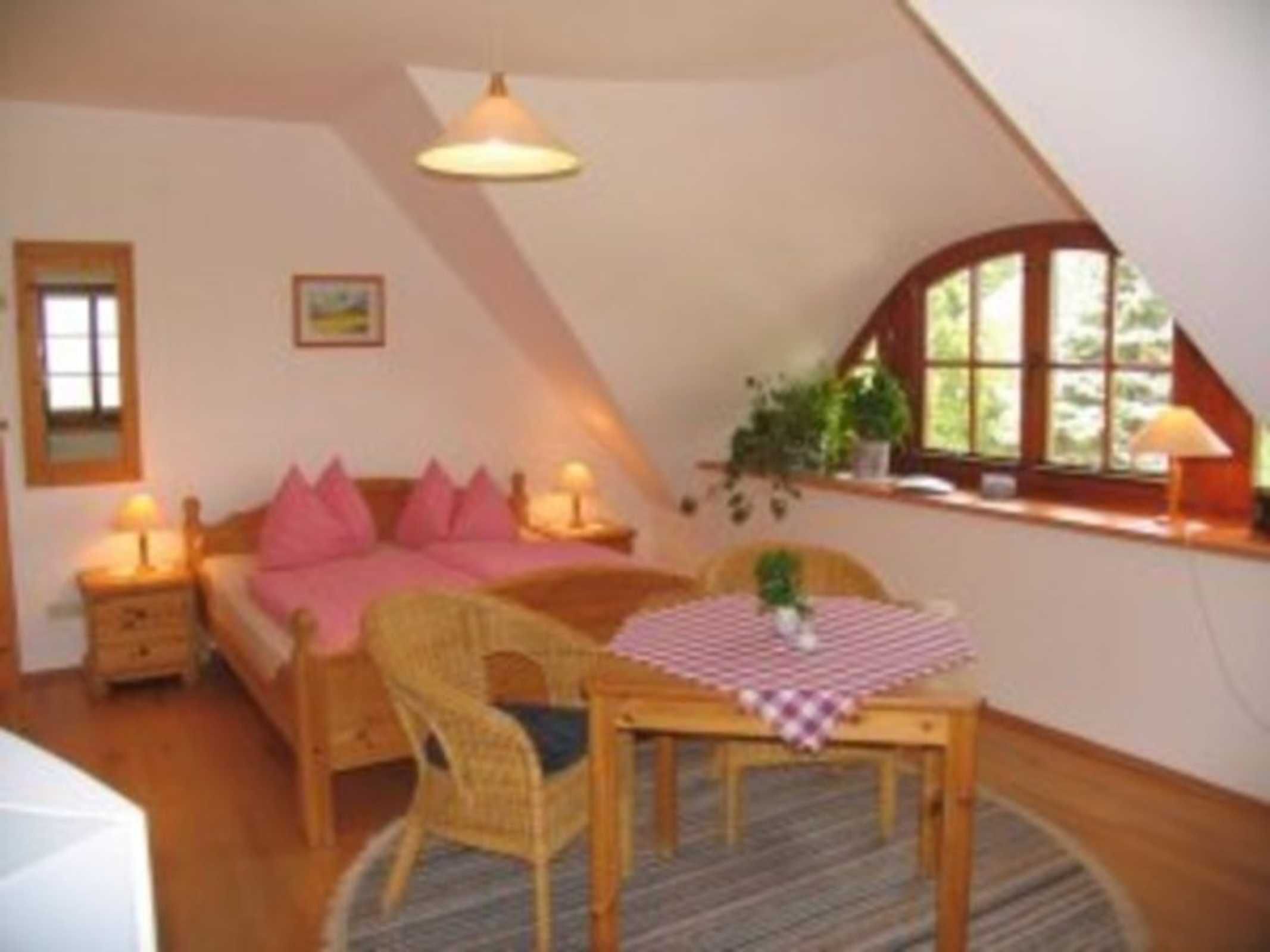 Een knus slaapkamer met een bed, nachtkastjes, een stoel, een tafel en een raam.