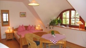 Ein gemütliches Schlafzimmer mit Bett, Nachttischen, einem Sessel, einem Tisch und einem Fenster.