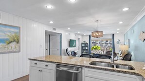 A modern kitchen with white cabinetry, granite countertops, and stainless steel appliances.