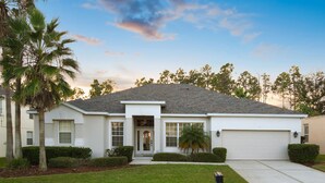 A single-story house with a front door, a garage, and a well-maintained lawn. - Experience magic! HR Golf Course view 5bd/3b w/pool-spa near all Disney Parks (Davenport)